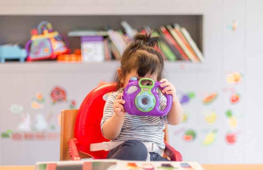 girl holding purple and green camera toy